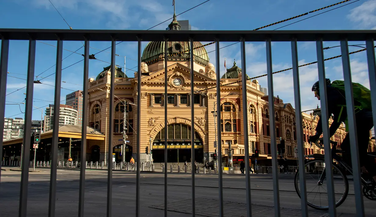 Pesepeda melewati Stasiun Flinders Street yang kosong selama lockdown atau penguncian wilayah di Melbourne, Kamis (6/8/2020). Negara bagian Victoria, hotspot COVID-19 di Australia, melakukan lockdown dan menutup bisnis ritel sebagai upaya mencegah penyebaran virus corona. (AP Photo/Andy Brownbill)