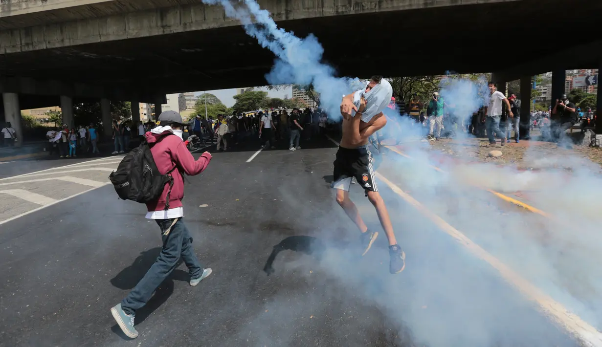 Petugas menghalau gas air mata yang dilemparkan para pengunjuk rasa di Caracas, Venezuela, (4/4). Para demonstran berusaha untuk menemani anggota parlemen oposisi dalam sesi wacana penghapusan Mahkamah Agung. (AP Photo / Fernando Llano)
