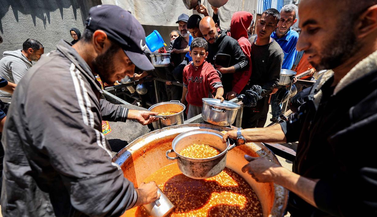 Situasi ini membatasi akses ke lahan pertanian, pasokan makanan, dan layanan penting. Tampak dalam foto, orang-orang berebut untuk mendapatkan makanan hangat di kamp pengungsi Palestina, Nuseirat, Jalur Gaza Tengah pada Kamis 7 Mei 2026. (Eyad Baba/AFP)