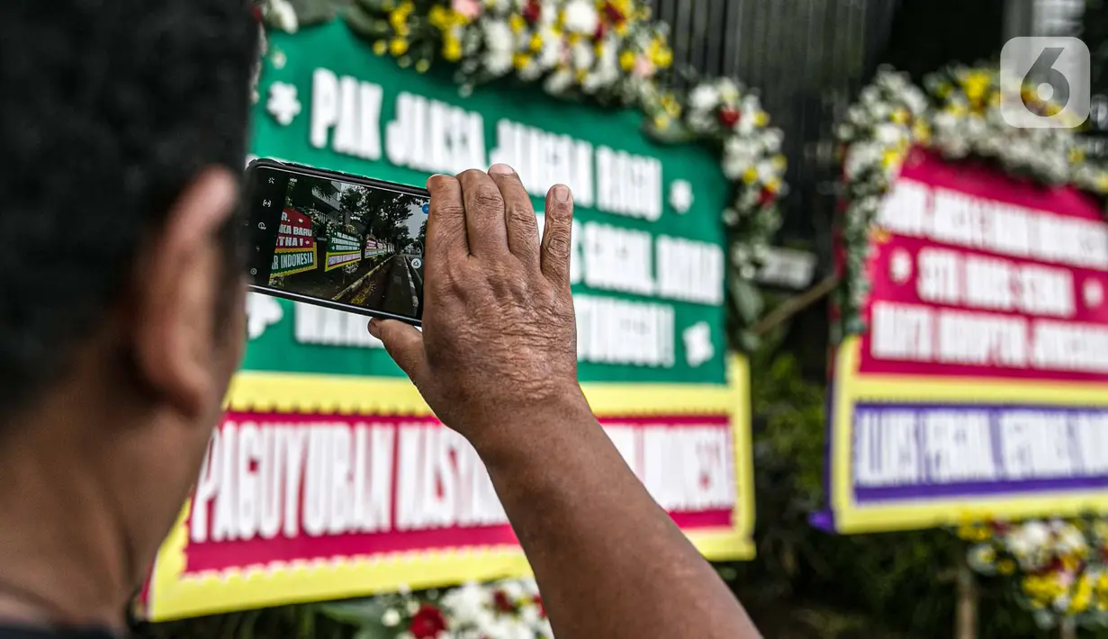 Warga mengambil foto karangan bunga di depan Gedung Kejaksaan Agung RI, Jakarta, Selasa (27/10/2020). Karangan bunga berasal dari korban terdampak kasus asuransi Jiwasraya yang mengharapkan kasus mega skandal itu bisa segera tuntas dan memberikan keadilan bagi mereka. (Liputan6.com/Faizal Fanani)