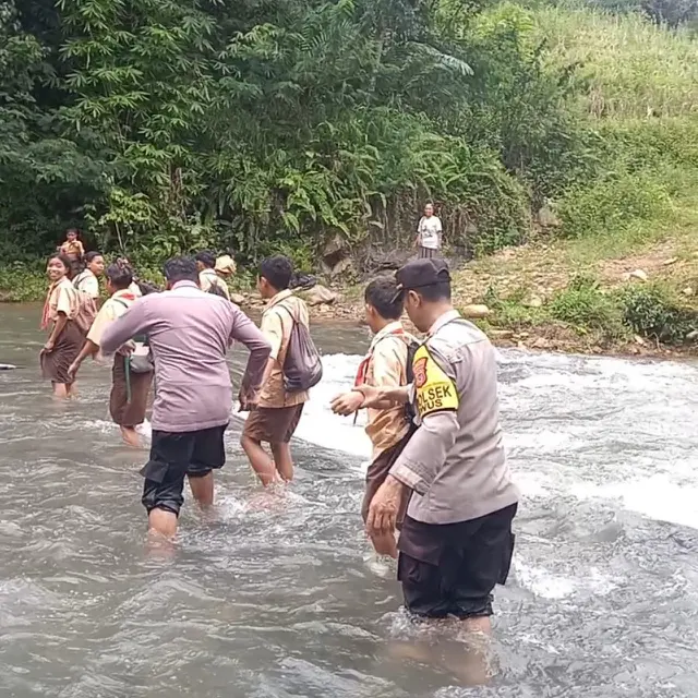 Anggota Polsek Kuwus, Kabupaten Manggarai Barat, NTT saat menggendong siswa nyebrang sungai ke sekolah