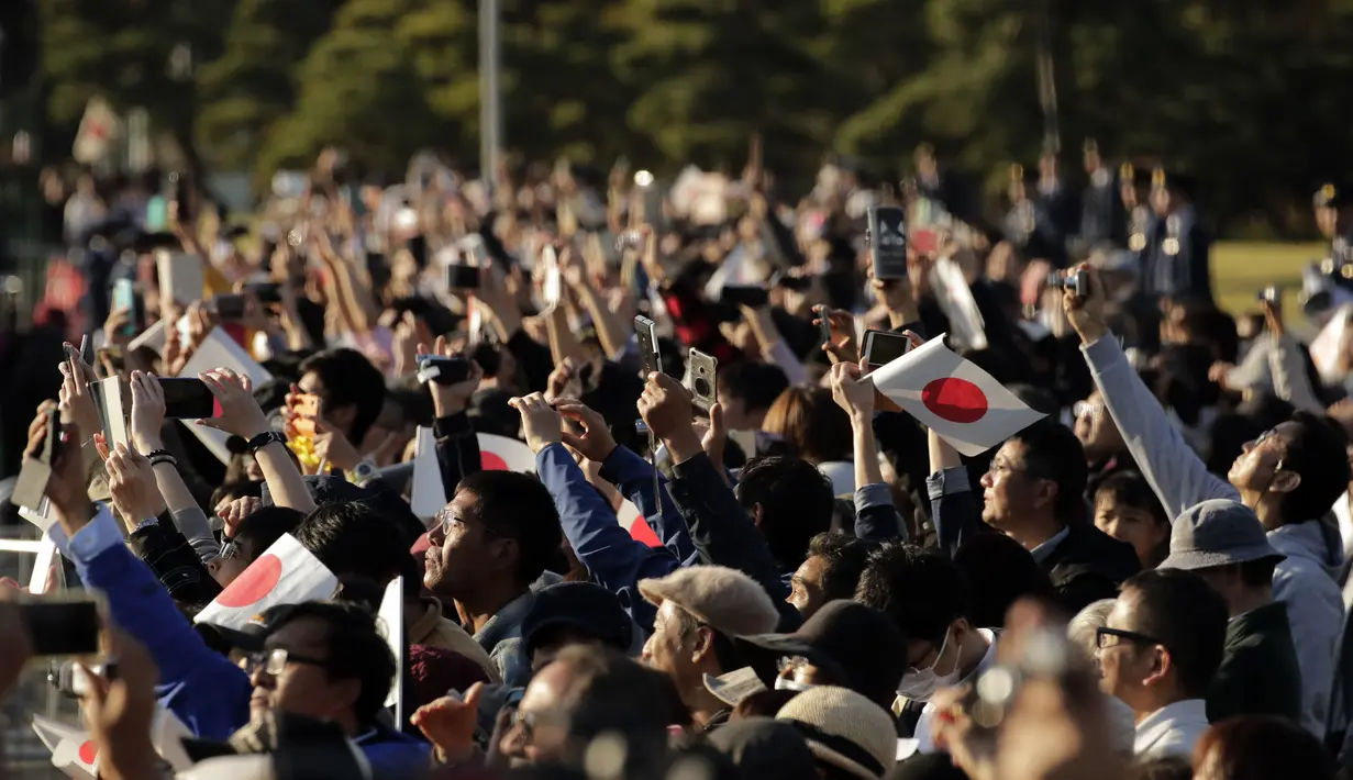 Ribuan warga mengabadikan parade Kaisar Naruhito dan Permaisuri Masako di Tokyo, Jepang, Minggu (10/11/2019). Diperkirakan sebanyak puluhan ribu warga memadati rute yang dilalui Kaisar Naruhito dan Permaisuri Masako. (AP Photo/Jae C. Hong)