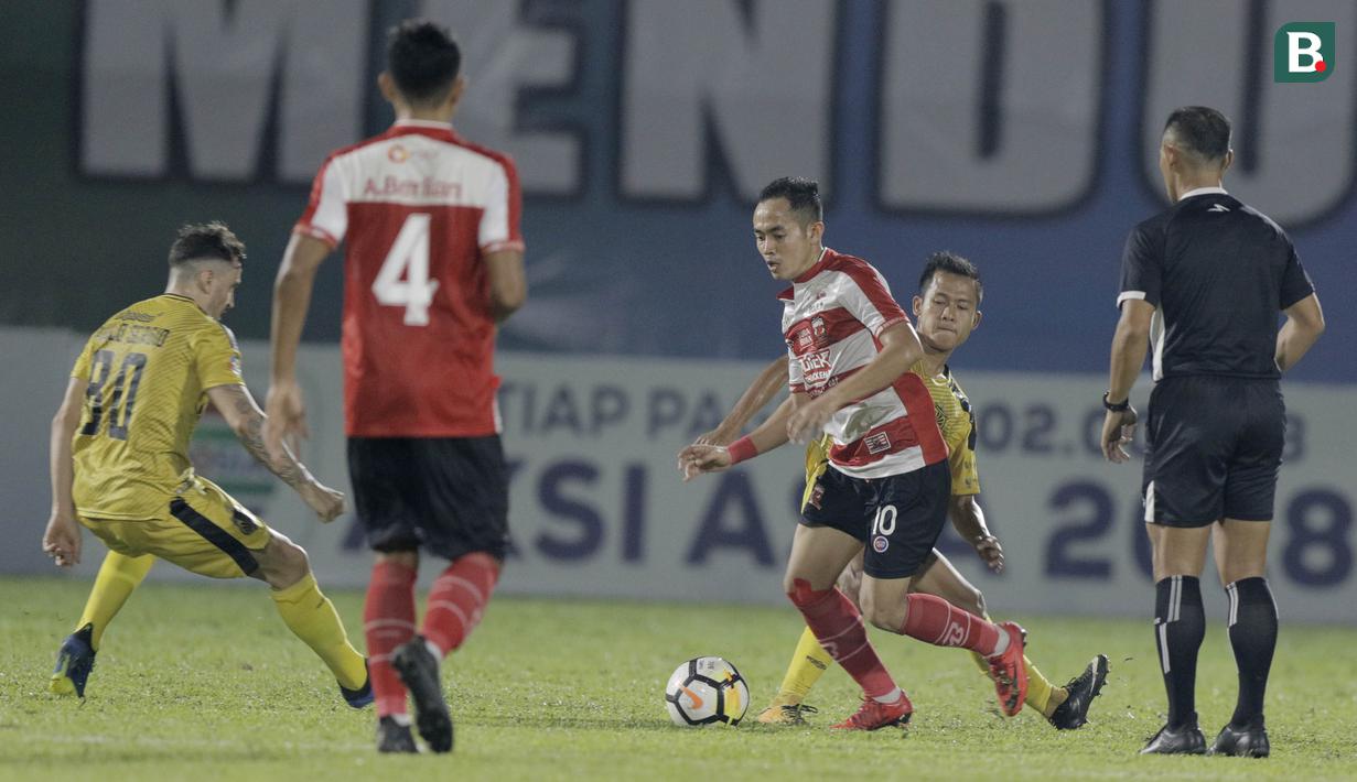 Gelandang Madura United, Slamet Nurcahyo, berusaha melewati Gelandang Bhayangkara FC, Wahyu Suboseto, pada laga Liga 1 di Stadion PTIK, Jakarta, Kamis, (07/6/2018). Bhayangkara FC menang 1-0 atas Madura United. (Bola.com/M Iqbal Ichsan)