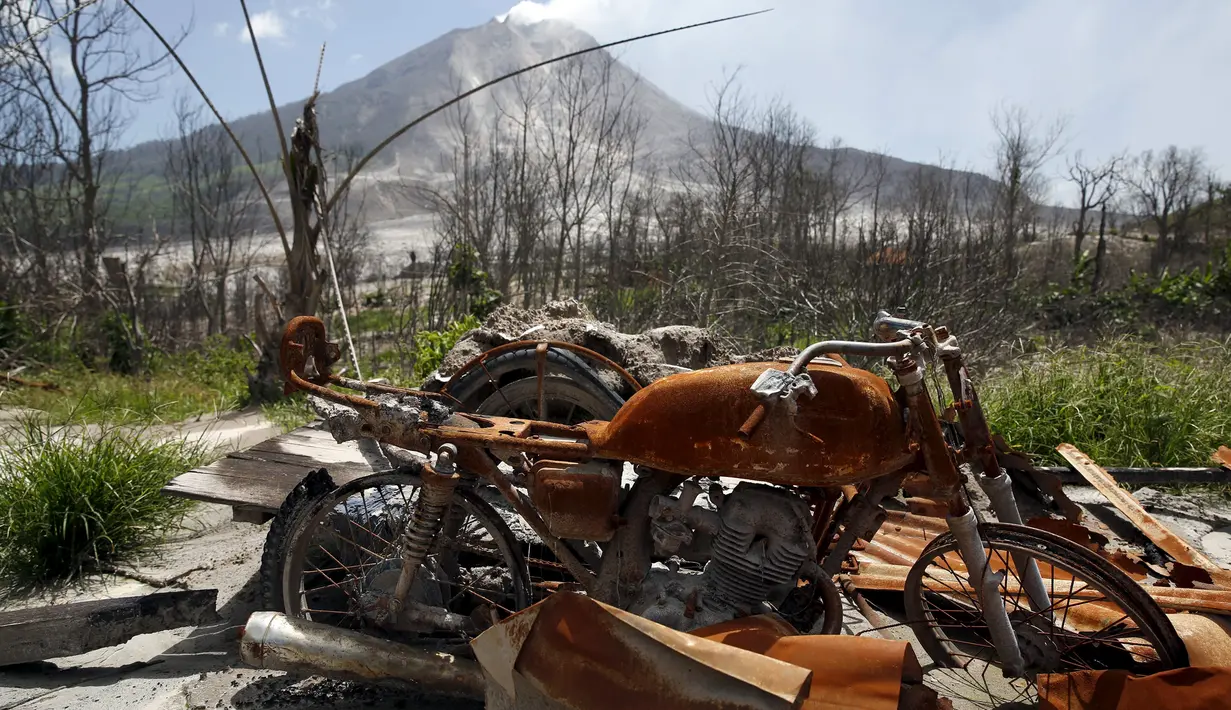 Sepeda motor yang terbakar lava panas dari Gunung Sinabung terlihat di perkebunan yang ditinggalkan warganya, di Desa Beras Tepu, Karo, Sumatera Utara, 21 Juni 2015. (REUTERS/Beawiharta)