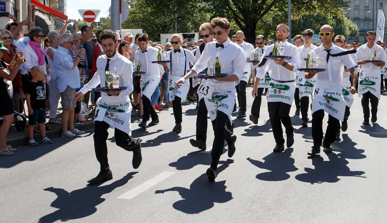 Aksi pramusaji berlari membawa nampan dalam Waiters Race ke-21 di Fetes de Geneve, Swiss, 6 Agustus 2017. Mereka beradu kecepatan sembari menjaga keseimbangan membawa nampan berisi dua gelas dan dua botol sejauh 1,8 km (Salvatore Di Nolfi/Keystone via AP)