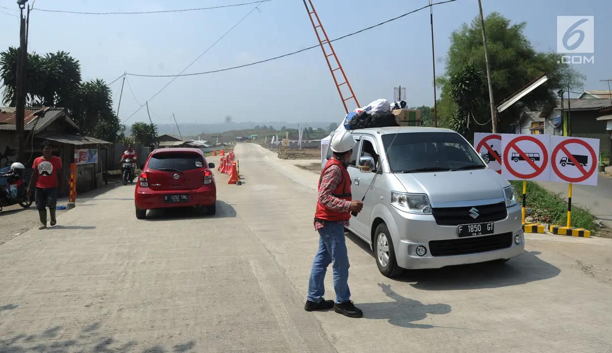 Petugas memberi arahan kepada pengguna mobil yang akan melintas di jalan fungsional Bocimi di kawasan Cigombong, Bogor (9/6). (Merdeka.com/Arie Basuki)