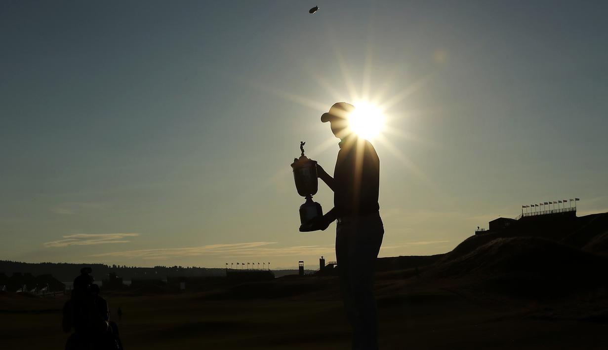 Foto siluet Jordan Spieth dengan trofi juara Turnamen Golf AS Terbuka yang berlangsung di Chambers Bay, University Place, Wash., AS. Minggu (21/6). (AP Photo/Charlie Riedel)
