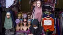 Seorang pedagang menggunakan telepon seluler pintarnya sambil menunggu pelanggan di sebuah kios pinggir jalan di Jakarta pada 30 Juni 2025. (BAY ISMOYO/AFP)