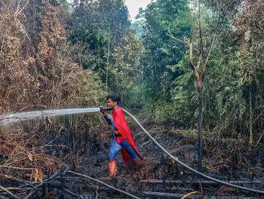 Pelajar bernama Rudiansyah dengan mengenakan kostum Superman membantu memadamkan kebakaran hutan dan lahan di Petuk Katimpun, Palangkaraya, Kalimantan Tengah, 17 Agustus 2026. (AFP/ Reina)