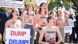 Sejumlah wanita bertelanjang dada sambil membawa poster tuntutan saat menggelar demo menolak Donald Trump di Burlingame, California (29/4). Para wanita ini menolak Donald Trump menjadi Presiden Amerika Serikat. (REUTERS/Noah Berger)
