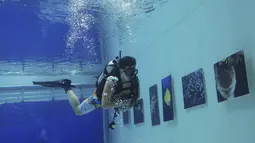 Penyelam melihat pameran foto yang dipamerkan dalam air di Inner Space Club, Beijing, China, Kamis (5/11). 40 karya foto bawah laut dipamerkan untuk memberikan pengalaman menyaksikan pameran foto yang tidak biasa kepada pengunjung (REUTERS/Kim Kyung-Hoon)