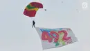 Penerjun payung membawa bendera HUT ke-492 DKI Jakarta saat Festival Damai Millenial Road Safety di Monas, Jakarta, Minggu (23/6/2019). Aksi ini diikuti puluhan penerjun payung dari personel gabungan TNI-Polri. (merdeka.com/Iqbal Nugroho)