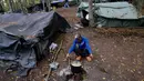 Seorang migran memasak dengan api terbuka di kamp darurat di hutan di luar Velika Kladusa, Bosnia pada 25 September 2020. Kebanyakan imigran dan pengungsi di Bosnia berasal dari Timur Tengah, Afrika dan Asia. (AP Photo/Kemal Softic)