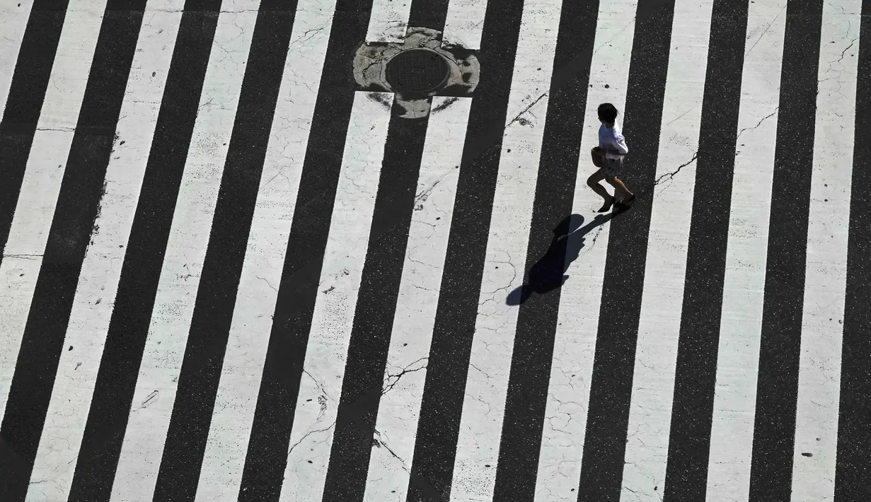 Seorang wanita berlari melintasi Shibuya Crossing yang juga disebut sebagai persimpangan pejalan kaki tersibuk dunia, di Tokyo, 13 Juni 2019. Di Shibuya Crossing ini juga dijadikan lokasi syuting dari film Fast & Farious: Tokyo Drift. (AP Photo/Jae C. Hong)