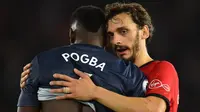 Striker Southampton, Manolo Gabbiadini, menghibur gelandang Manchester United, Paul Pogba, usai laga Premier League di Stadion St Mary, Manchester, Sabtu (1/12). Kedua klub bermain imbang 2-2. (AFP/Glyn Kirk)