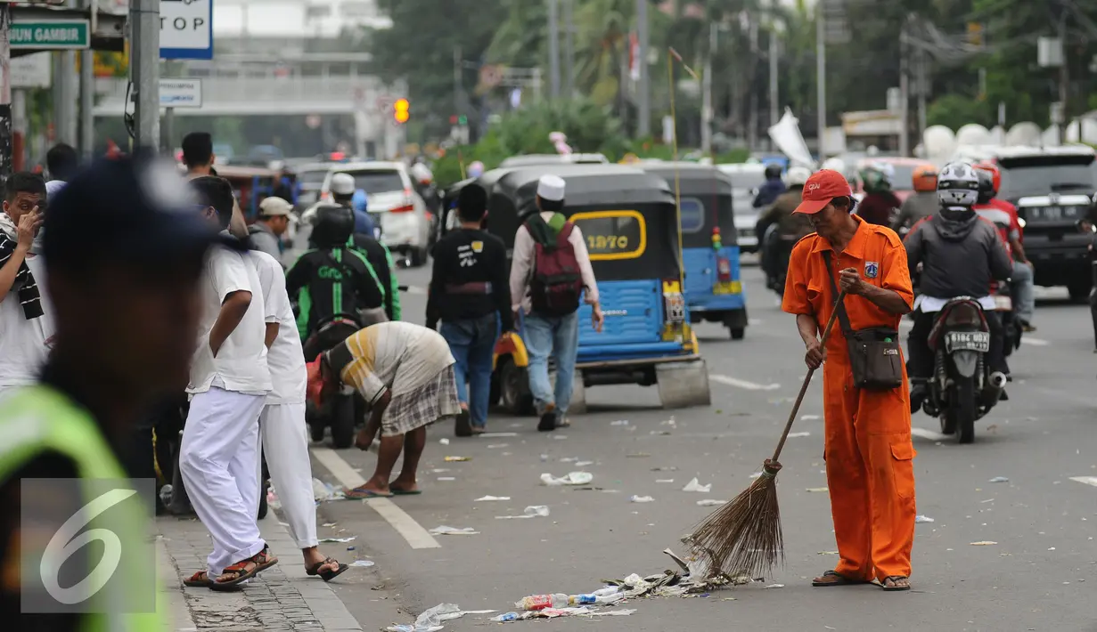 Petugas kebersihan DKI Jakarta membersihkan ceceran sampah di Silang Tenggara Monas, Jakarta, Jumat (14/10). Sebelumnya, ribuan massa ormas berunjuk rasa mendesak mundur Gubernur DKI Jakarta, Basuki Tjahaja Purnama. (Liputan6.com/Helmi Fithriansyah)
