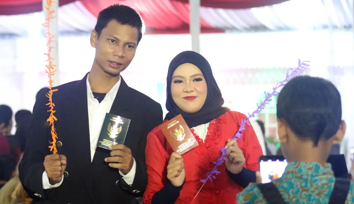 Pasangan peserta nikah massal berfoto sambil menunjukan buku nikah usai pelaksanaan itsbat nikah di Balai Kota DKI Jakarta, Selasa (31/12/2019). Melalui acara ini, pasangan yang baru menikah maupun yang hanya mengesahkan pernikahannya langsung tercatat di Disdukcapil. (Liputan6.com/Helmi Fithriansya