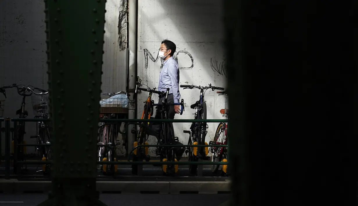 Seorang pria yang mengenakan masker pelindung untuk membantu mengekang penyebaran virus corona COVID-19 berjalan di Tokyo, Jepang, Senin (12/10/2020). Tokyo mengonfirmasi lebih dari 70 kasus COVID-19 pada hari Senin. (AP Photo/Eugene Hoshiko)