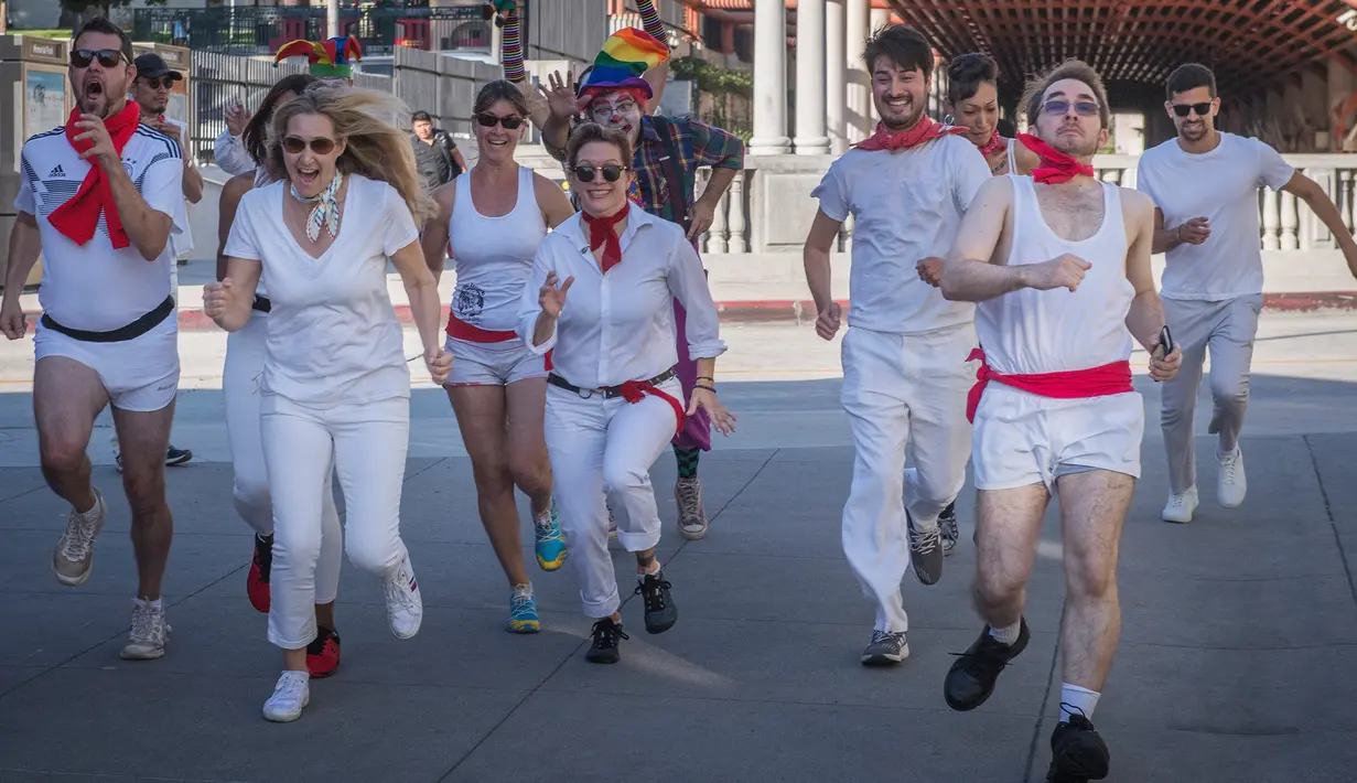 Peserta berdandan seperti badut mengajar pejalan kaki selama acara parodi tahunan "Running of the Clowns" i Pasadena, California pada 20 Oktober 2019. Lari dikejar kawanan badut ini merupakan parodi yang mengolok-olok lomba dikejar banteng di Spanyol. (Mark RALSTON / AFP)