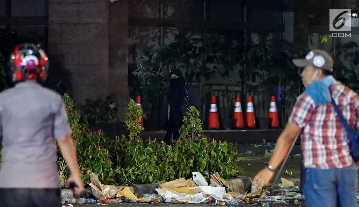 Seorang perempuan bercadar hitam dengan kabel menjuntai di tangan berusaha mendekat Gedung Bawaslu, Jakarta, Rabu (22/5/2019). Perempuan misterius yang berjalan sendiri tanpa massa ini mengenakan baju gamis warna hitam. (Liputan6.com/Immanuel Antonius)