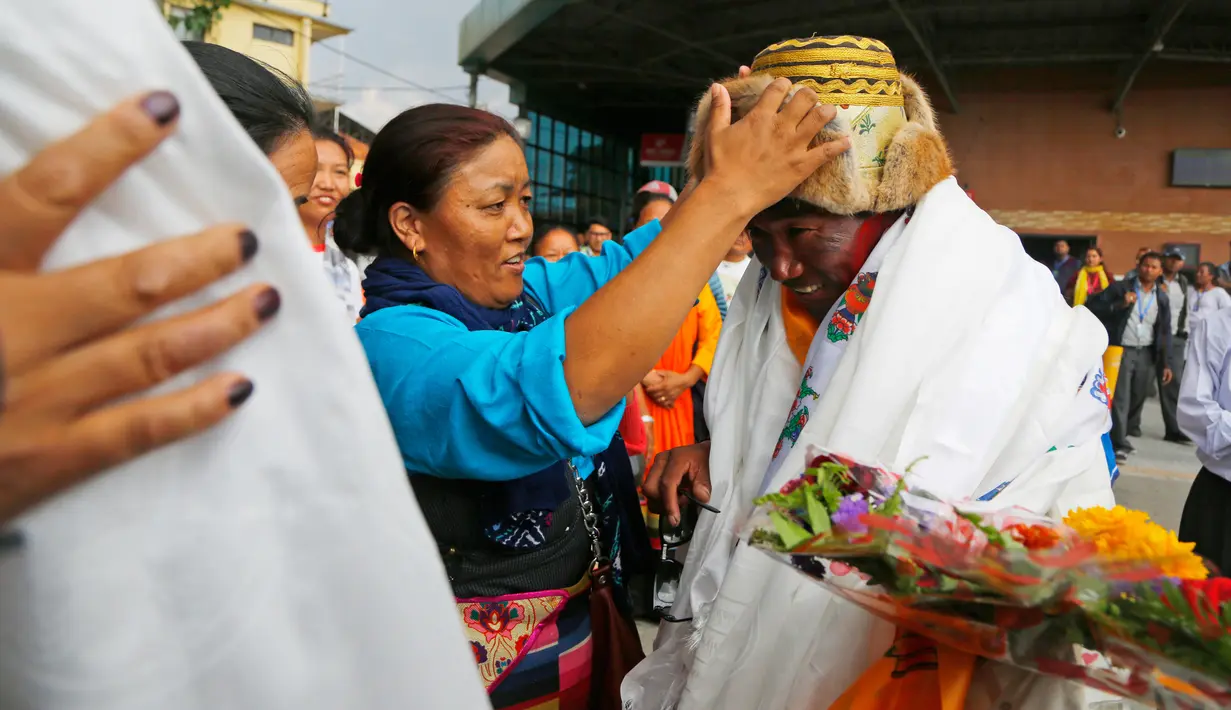 Teman dan keluarga memberikan topi kepada Kami Rita, seorang pemandu profesional, setibanya di Kathmandu, Nepal, 20 Mei 2018. Kami Rita mencatatkan rekor luar biasa dengan menaklukkan puncak Everest ke-22 kalinya. (AP/Niranjan Shrestha)
