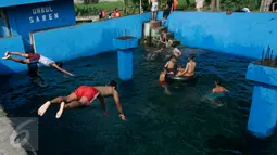 Dua orang anak melompat ke kolam pemandian Umbul Saren di Wedomartani, Sleman, Minggu (5/6). Pengunjung memadati kolam pemandian tersebut untuk melaksanakan tradisi "padusan" menjelang Ramadan 2016. (Liputan6.com/Boy Harjanto)