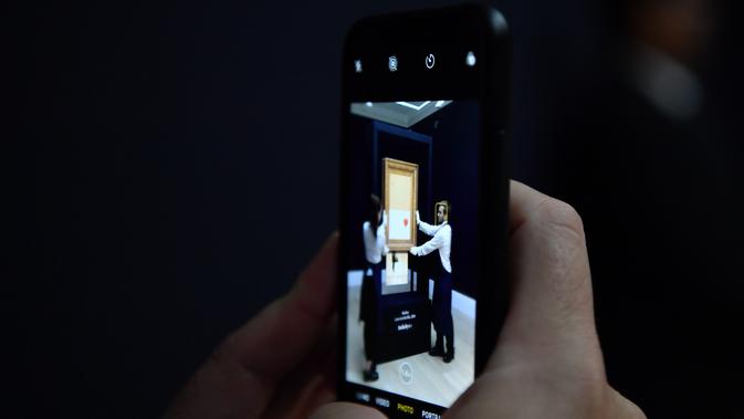 Jurnalis menggunakan smartphone mengambil gambar lukisan 