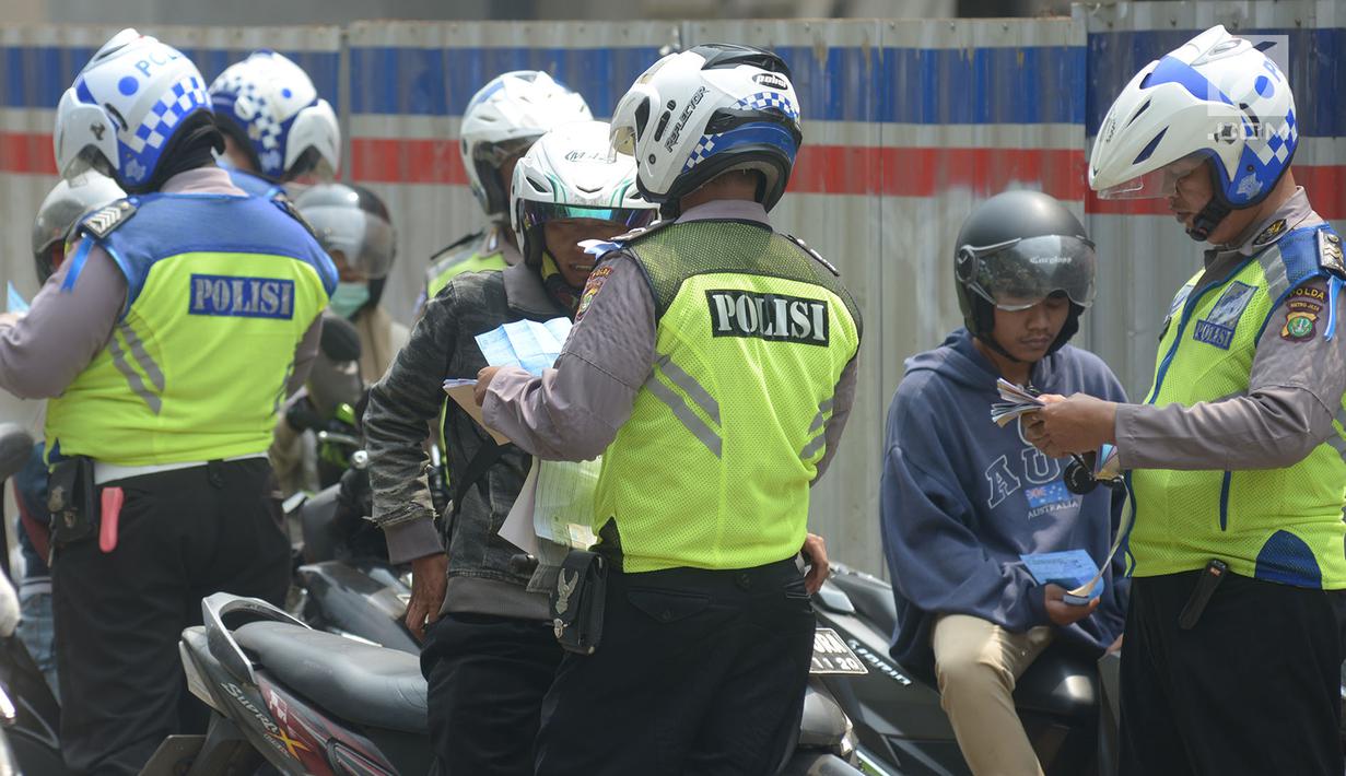 Polisi lalu lintas melakukan tilang terhadap pengendara motor saat razia Operasi Patuh Jaya 2019 di kawasan Kebon Nanas, Jakarta, Kamis (29/8/2019). Operasi ini diharapkan dapat meningkatkan kepatuhan dan ketertiban dalam berlalu lintas serta mengurangi angka kecelakaan. (merdeka.com/Imam Buhori)