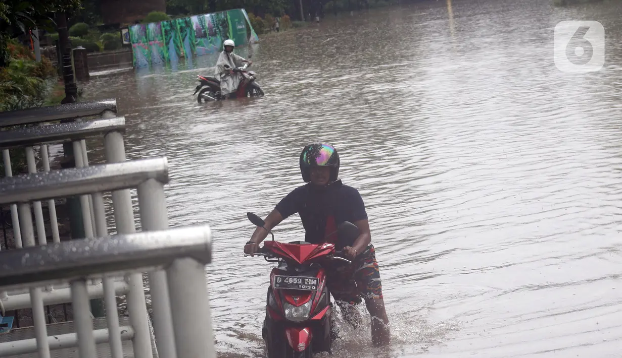 Pengendara mendorong kendaraannya saat melintasi Jalan Di Panjaitan dekat Halte Transjakarta Cawang Soetoyo yang banjir, Jakarta, Rabu (1/1/2020). Hujan yang mengguyur Jakarta sejak Selasa sore (31/12/2019) mengakibatkan banjir di sejumlah titik di Jakarta. (Liputan6.com/Helmi Fithriansyah)