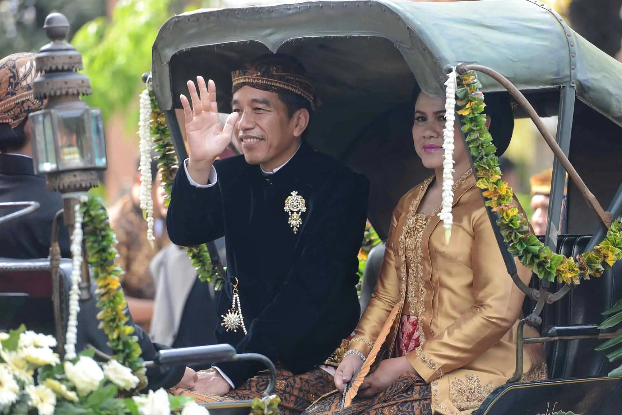 Dengan Kereta Kencana, rombongan keluarga besar Presiden Joko Widodo saat itu hendak menuju ke lokasi pernikahan Kahiyang dan Bobby di Graha Saba Buana. Lambaian tangan dan senyuman terus diberikan Jokowi. (Adrian Putra/Bintang.com)