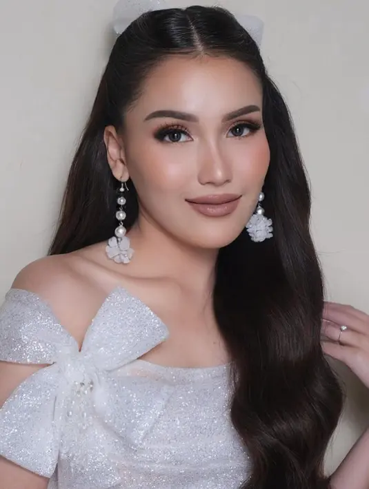 Ayu mengaplikasikan makeup glam, dengan lipstik coklat glossy membuat bibirnya tampak bervolume. Riasan mata dengan bulu mata penuh dan eyeshadow shimmer coklat. [@kriznafahrezi]