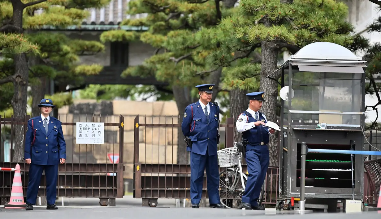 Polisi berdiri di depan pintu masuk halaman Istana Kekaisaran Jepang (29/4/2019). Kaisar Jepang Akihito akan turun dari Tahta Krisan pada 30 April 2019 yang pertama dalam keluarga kekaisaran dan tertua di dunia selama dua abad, atau selama 30 tahun masa pemerintahan. (Charly Triballeau / AFP)
