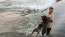 Seorang pria memandikan anjingnya di pinggir sungai Nil karena cuaca disana hingga 47 derajat Celcius, Kairo, Mesir, Rabu  (12/8/2015). Gelombang panas di Mesir menewaskan paling tidak 61 orang dalam tiga hari terakhir. (REUTERS/Mohamed Abd El Ghany)