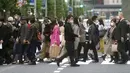 Orang-orang yang mengenakan masker untuk membantu mengekang penyebaran virus corona COVID-19 berjalan melintasi penyeberangan pejalan kaki di Tokyo, Jepang, Rabu (28/10/2020). Tokyo mengonfirmasi lebih dari 170 kasus virus corona COVID-19 baru pada 28 Oktober 2020. (AP Photo/Eugene Hoshiko)