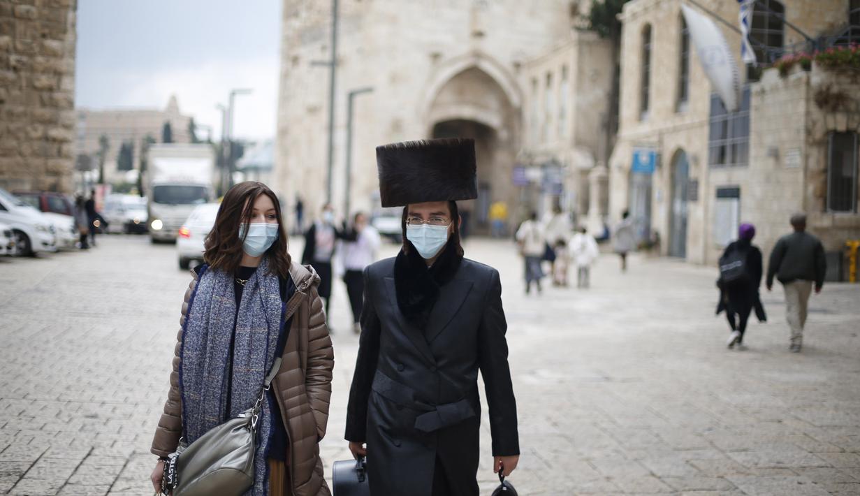 Wanita dan pria mengenakan masker berjalan di luar Kota Tua Yerusalem di tengah pandemi COVID-19 (25/11/2020). (Xinhua/Muammar Awad)