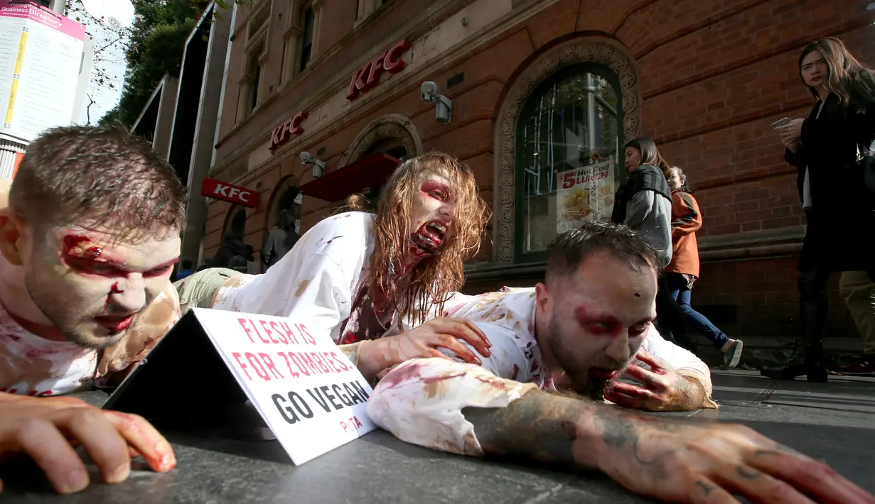 Aktivis PETA berdandan menyerupai zombie sambil berbaring di jalan depan sebuah restoran cepat saji di Sydney, Australia, Kamis (15/6). Aksi tersebut sebagai bentuk protes terhadap konsumsi daging dan mempromosikan vegetarian. (AP Photo/Rick Rycroft) 
