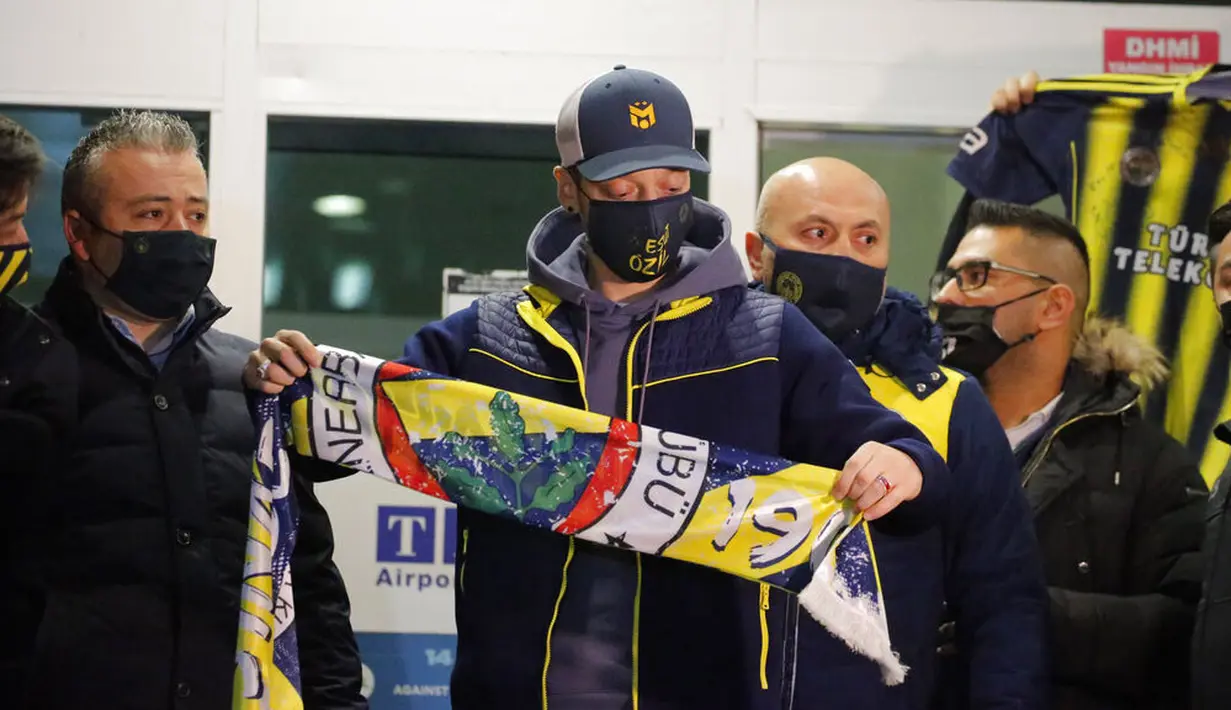 Pesepak bola asal Jerman, Mesut Ozil, menunjukan syal Fenerbahce saat tiba di Bandara Ataturk, Turki, Senin (18/1/2021). Setelah memutuskan hengkang dari Arsenal, Ozil akan memperkuat klub asal Turki, Fenerbahce. (AP Photo)