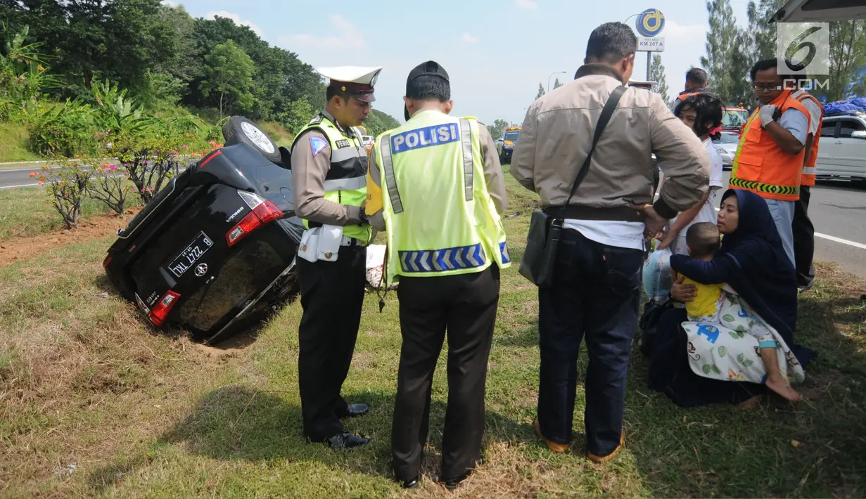 Petugas kepolisian mendata penumpang mobil Innova yang terbalik di KM 208 Tol Palikanci (Palimanan-Kanci), Jawa Barat, Rabu (21/6). Tak ada korban jiwa dalam kecelakaan yang diduga karena sopir mobil B 2247 TKL itu mengantuk. (Liputan6.com/Gempur M Surya)