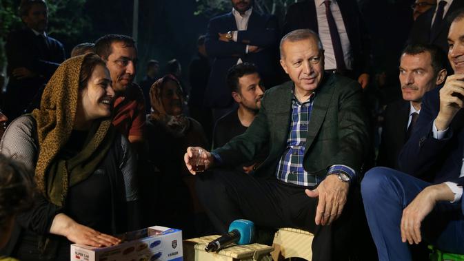 Presiden Turki, Tayyip Erdogan berbincang dengan sjeumlah orang saat berbuka puasa bersama warga di sebuah taman di Istanbul pada Senin (27/5/2019). Buka puasa bersama tersebut dilakukan Erdogan agar lebih dekat dengan warganya. (Murat Kula/Presidential Press Office/Handout via REUTERS)