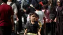 Seorang anak laki-laki Palestina yang sedang bermain membawa sepanci makanan yang ia terima dari sebuah tempat penampungan tempat tinggal keluarga-keluarga di Nuseirat, pusat Jalur Gaza, pada 2 November 2025. PBB juga menyerukan agar semua titik perbatasan dibuka dan lebih banyak lembaga kemanusiaan diberi izin membawa bantuan ke Gaza. (EYAD BABA/AFP)
