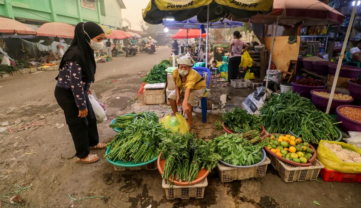 Seorang perempuan mengenakan masker saat membeli sayuran di pasar tradisional di tengah kabut asap tebal akibat kebakaran hutan dan lahan di Palangkaraya, Kalimantan Tengah, Senin (12/10/2026). Kabut asap menyelimuti sejumlah wilayah di Indonesia, Malaysia, dan Singapura selama beberapa pekan terakhir akibat kebakaran yang melanda kawasan hutan di Kalimantan dan Sumatra. Asap kebakaran terbawa angin hingga melintasi wilayah regional dan berdampak pada kualitas udara. (REINA/AFP)