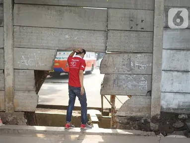 Pejalan kaki melewati tembok berlubang di Terminal Kampung Rambutan, Jakarta, Kamis (19/12/2019). Jauhnya akses bagi pejalan kaki menjadikan tembok berlubang tersebut pintu alternatif untuk keluar dan masuk Terminal Kampung Rambutan. (Liputan6.com/Immanuel Antonius)