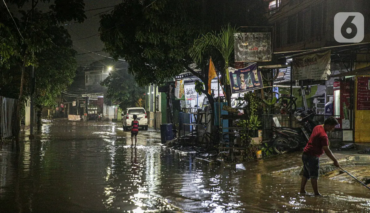 Warga membersihkan depan rumah yang tergenang banjir di kawasan Mampang Prapatan, Jakarta, Sabtu (13/11/2021). Intensitas hujan yang tinggi sejak sore di Jakarta membuat kawasan permukiman di Mampang Prapatan tergenang banjir dengan tinggi sebetis orang dewasa. (Liputan6.com/Faizal Fanani)