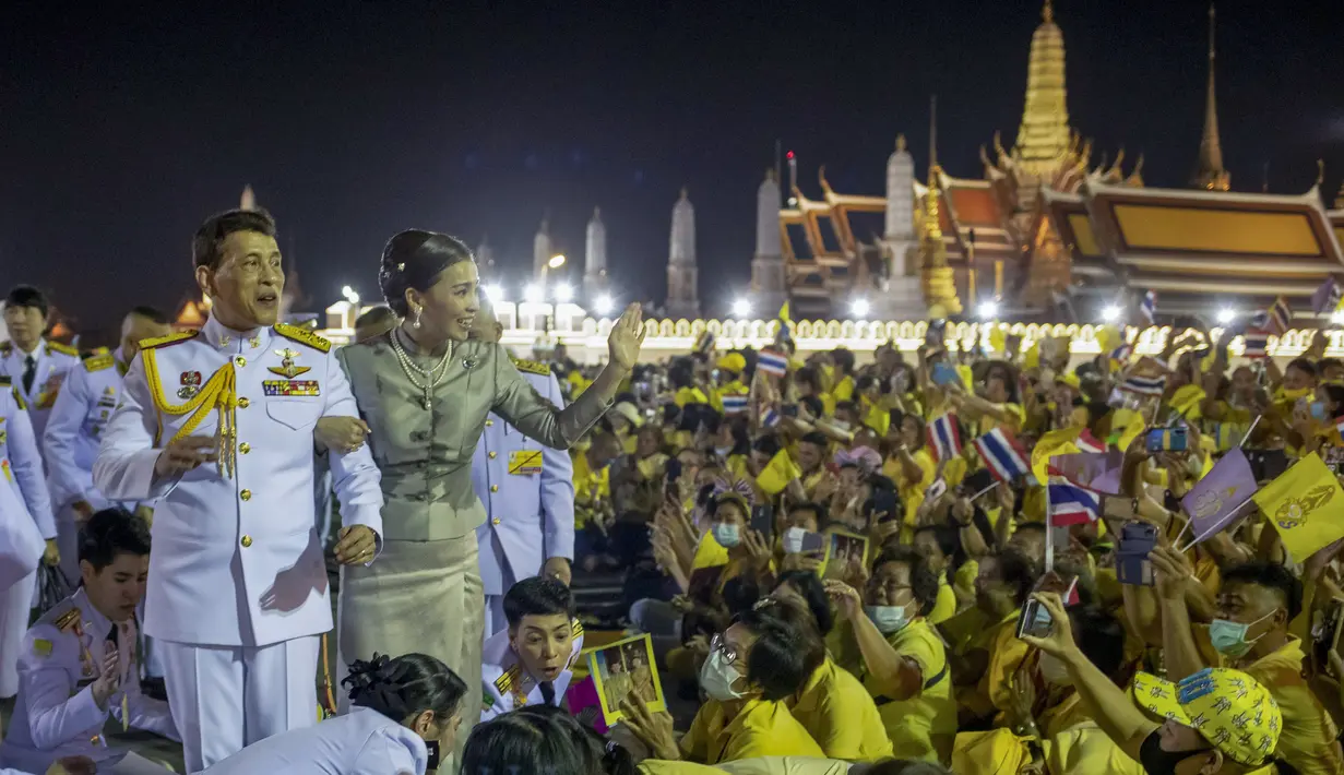 Raja Maha Vajiralongkorn dan Ratu Suthida melambaikan tangan ke pendukungnya di Bangkok, Thailand, Minggu (1/11/2020). Di bawah tekanan yang meningkat dari pengunjuk rasa yang menuntut reformasi pada monarki, Raja dan Ratu Thailand bertemu dengan ribuan pendukungnya. (AP Photo/Wason Wanichakorn)