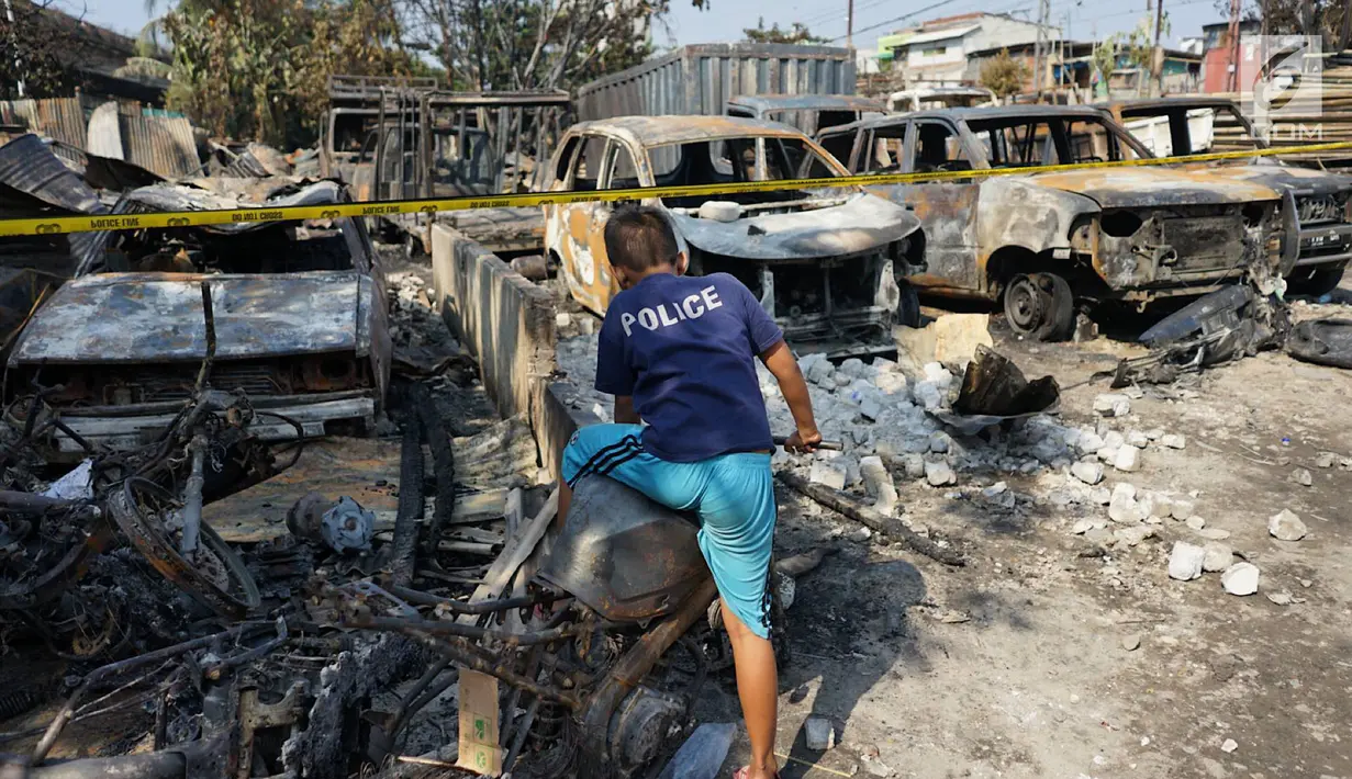 Seorang anak menaiki sepeda motor yang hangus terbakar usai kebakaran melanda lahan parkir di Jalan Budi Mulia Utara, Pademangan, Jakarta Utara, Rabu (24/7/2019). Kebakaran menghanguskan 14 mobil, 5 sepeda motor, dan 3 bedeng serta seorang warga mengalami luka bakar. (Liputan6.com/Immanuel Antonius)