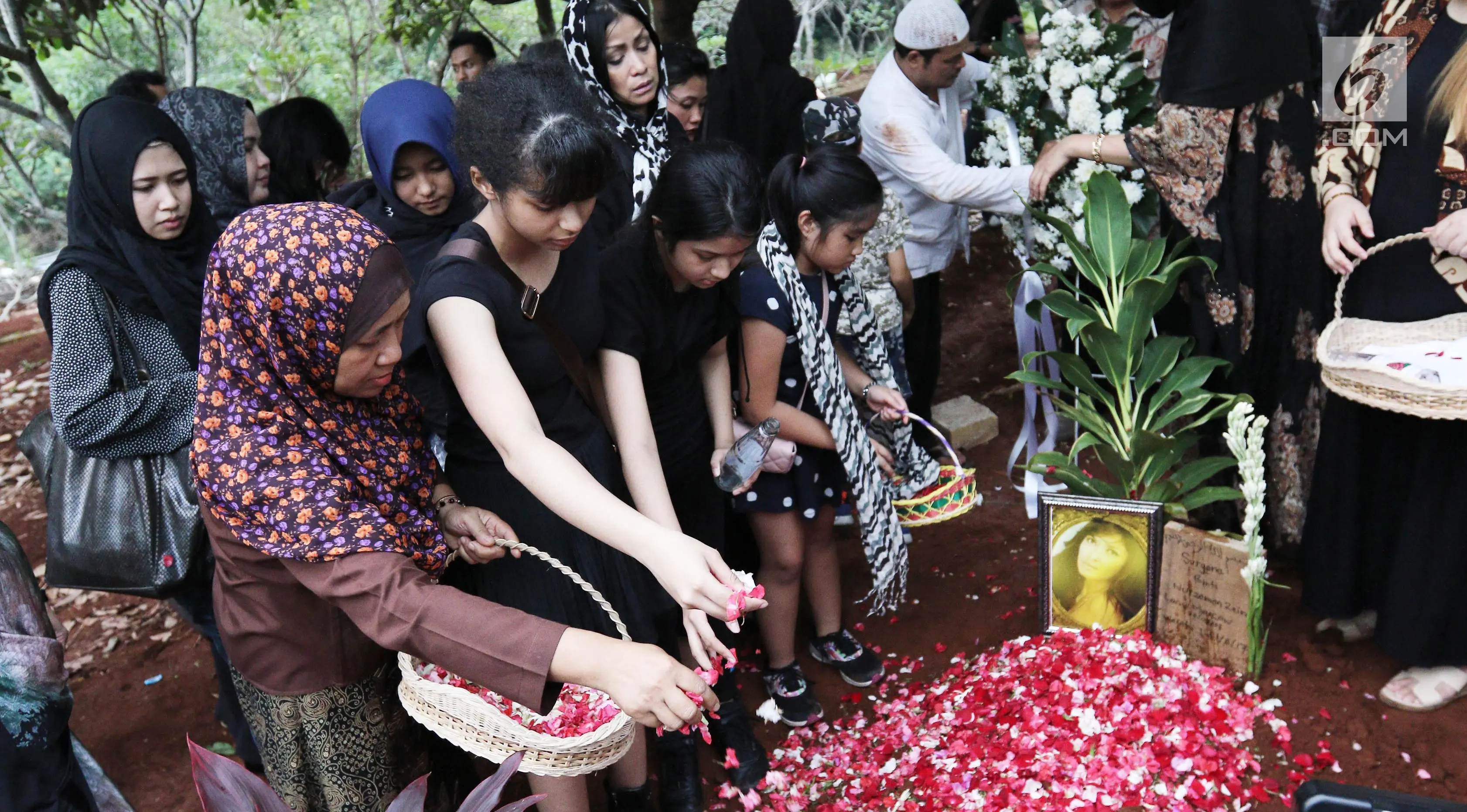 Penaburan bunga di atas makam Yana Zein di TPU Gandul, Cinere, Depok, Jumat (2/6). Yana Zein meninggal pada kamis (1/6/2017), karena kanker payudara stadium VI yang dideritanya. (Liputan6.com/Herman Zakharia)