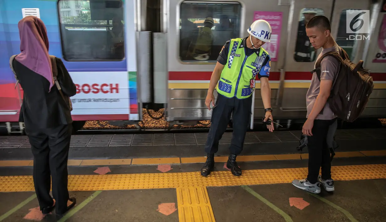 Petugas berjaga di garis antrean penumpang saat menunggu KRL di Stasiun Juanda, Jakarta, Kamis (10/8). PT KAI Commuter Jabodetabek melakukan uji coba garis antrean penumpang tersebut guna untuk keselamatan bagi para penumpang. (Liputan6.com/Faizal Fanani)