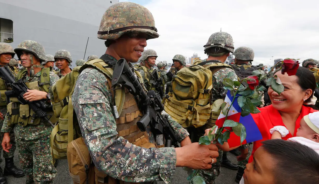 Tentara Filipina menerima bunga mawar merah usai bertempur di kota Marawi saat turun dari kapal amfibi Angkatan Laut Filipina BRP Tarlac di Manila, Filipina (30/10). Kota Marawi berhasil direbut dari para militan. (AP Photo / Bullit Marquez)