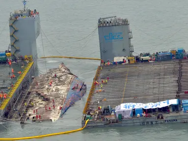 Pekerja mempersiapkan diri mengangkat bangkai kapal feri Sewol di pulau barat daya Jindo, Korea Selatan, Kamis (23/3).Feri Sewol yang tenggelam hampir tiga tahun lalu dari kedalaman 44 meter muncul untuk pertama kalinya (Park Gyung-woo/Hankookilbo via AP)