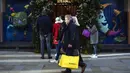 Orang-orang berjalan melewati toko sambil membawa tas belanja di Mayfair setelah pelonggaran pembatasan virus corona COVID-19 menyusul berakhirnya kebijakan penguncian nasional atau lockdown kedua di Inggris, di London, Sabtu (5/12/2020). (AP Photo/Alberto Pezzali)